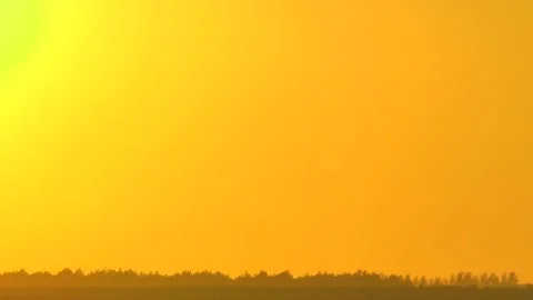 Sunset of the flaring sun against the background of an orange clear sky. Видео 70070184