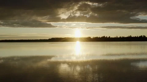 Sunset fly over calm lake and low flying clouds. Sun is reflected in lake Stock Footage 116480293