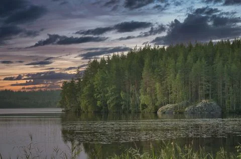 Sunset at the forest lake with reflection and rocks, peaceful natural scenery Stock Photos