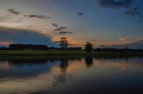 Sunset with forests by the river, with reflection in the water Stock Photos