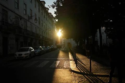 Sunset glaring between building beaming onto a street crossing Stock Photos