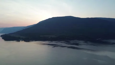 Sunset Glow Behind a Mountain on a Calm Lake Stock Footage 318816918