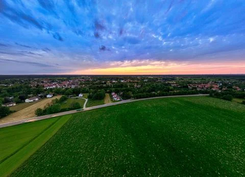 Sunset Glow Over Green Fields and Distant Town Stock Photos