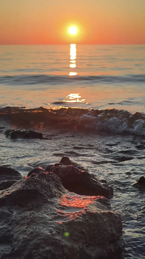 Sunset glow over ocean waves on rocky shore. Waves oncoming on stone, surf on Stock Footage 328918333
