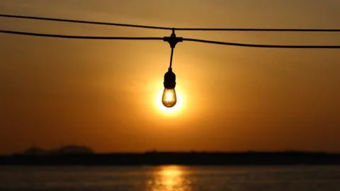 Sunset with Glowing Light Bulb Over Water Stock Photos