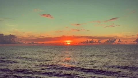 Sunset glowing over the calm ocean with colorful clouds in the sky creating.. Stock Footage 338281809