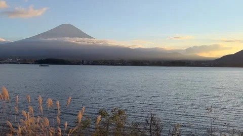 Sunset glows on Lake Kawaguchi as Mount Fuji appears through soft autumn clouds Stock Footage 324021891