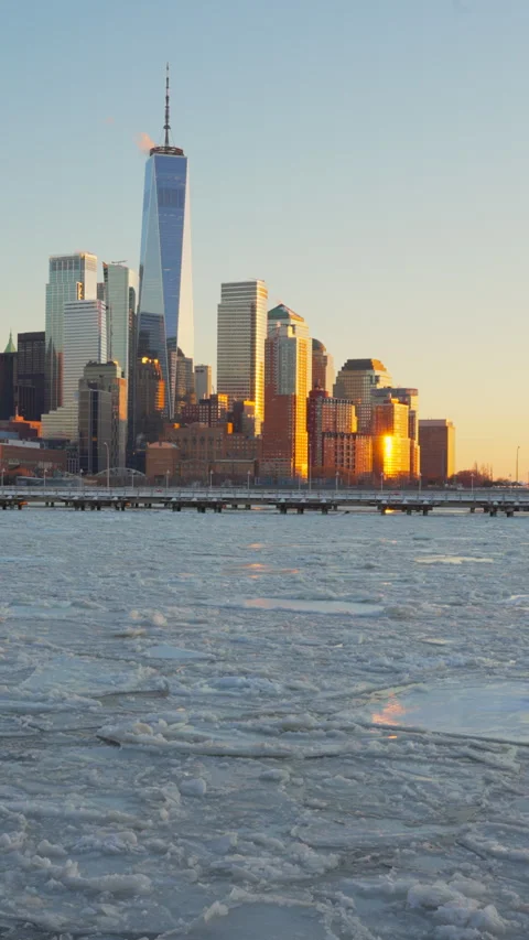 The sunset glows Lower Manhattan skyscraper and Ice floes on frozen Hudson River Vídeo Stock 336706481