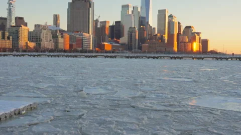 The sunset glows Lower Manhattan skyscraper and Ice floes on frozen Hudson River Vídeos de archivo 336707167