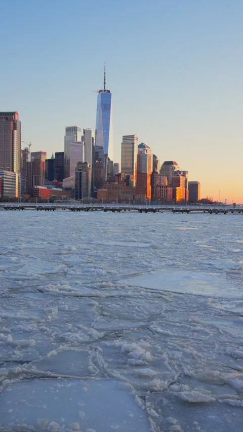 The sunset glows Lower Manhattan skyscraper and Ice floes on frozen Hudson River Video stock 336708981
