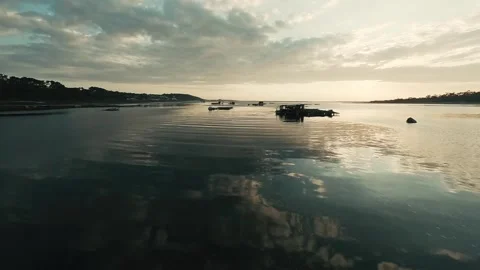 Sunset glows over calm water, reflecting clouds and distant trees Stock Footage 340227585