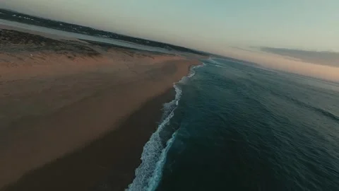 Sunset glows over calm waves lapping golden sand Stock Footage 340227765