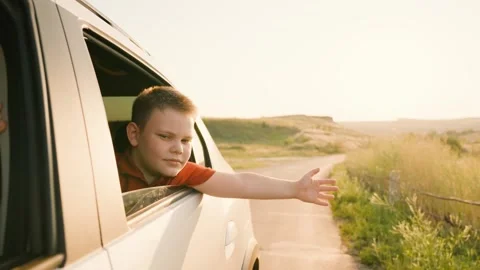 Sunset hand movement, waving his hand out car window, happy boy son kid car Stock Footage 281459983