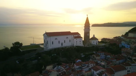 Sunset harbor view with church tower silhouette over red rooftops in Piran Stock Footage 318967600