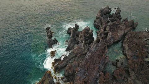 Sunset highlights the earthy tones of rugged, coastal formations and ocean waves Stock Footage 306530933