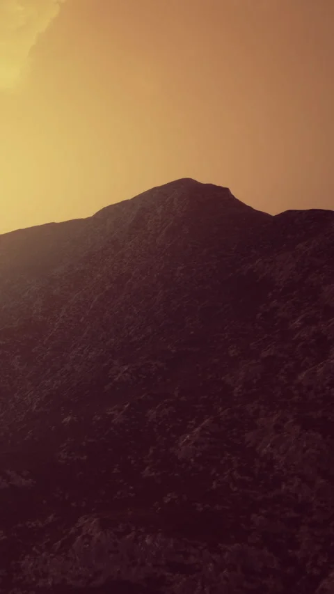 Sunset hues paint the rugged mountain landscape in warm golden tones Stock Footage 334252098