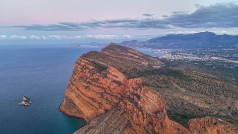 Sunset illuminates layered cliffs with nearby offshore rock formation and Stock Footage 342361002