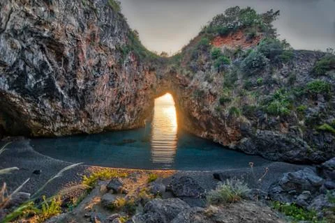 Sunset inside a beautiful rock arch on the sea Stock Photos