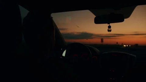 Sunset from inside car and blurry headlights of oncoming automobiles on highway 库存影片 247690862