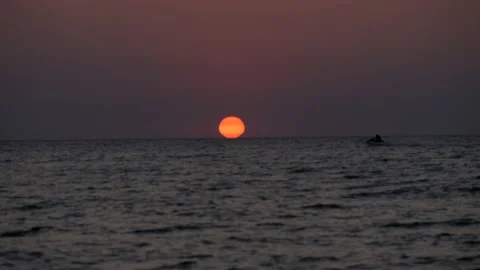 Sunset. The jet ski sweeps against the background of the red sun setting over Stock Footage 204152838