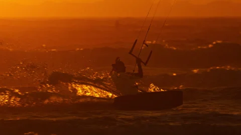 Sunset kiteboarding session as guy carves through water Stock Footage 337560265