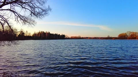Sunset at the lake with clear blue sky and gentle ripples on the water Stock-Footage 332636255