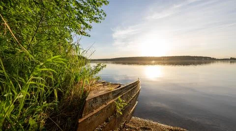 Sunset on the lake with a damaged boat Stock Photos