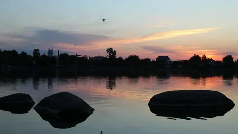 Sunset, lake, large stones are in the water, small waves on the water Stock Footage 211437879