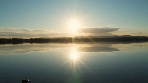 A sunset on the lake with a mirror image of the sun and sky on the water. Stock Footage 276353619