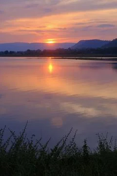 Sunset lake mountain landscape reflection water sky form warm light across .. Stock Photos