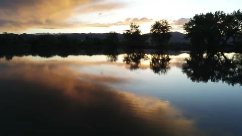 Sunset in lake by mountains - Drone camera moves forward and up Video stock 137860488