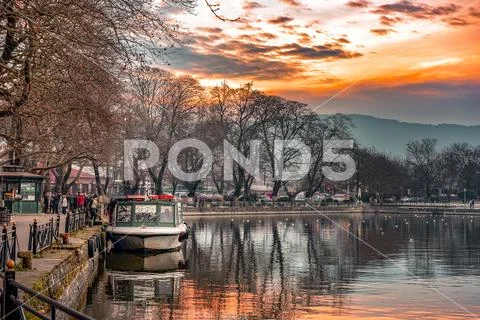 Sunset on lake Pamvotis. Docked boat ready to transfer people to the small is Stock Photos