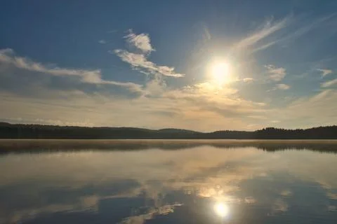 Sunset at the lake with reflection and forest, peaceful evening atmosphere Stock Photos