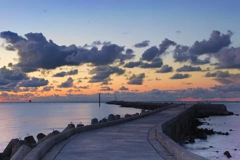 Sunset landscape with dark clouds and pier Stock Photos