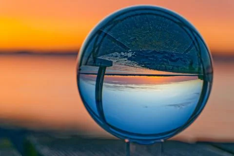 Sunset landscape reflected through a clear glass sphere with vibrant sky colo Stock Photos