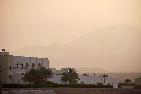 Sunset landscape with remote hotel complex against dark mountain peaks in Stock Photos