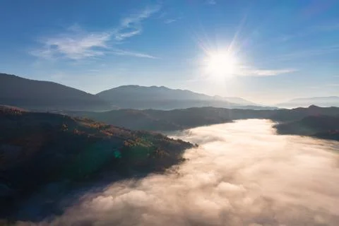 Sunset light among clouds above mountainous canyon in mist Stock-Fotos