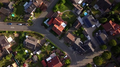 Sunset light bathes red-tiled rooftops along residential street intersection in Stock Footage 340540923