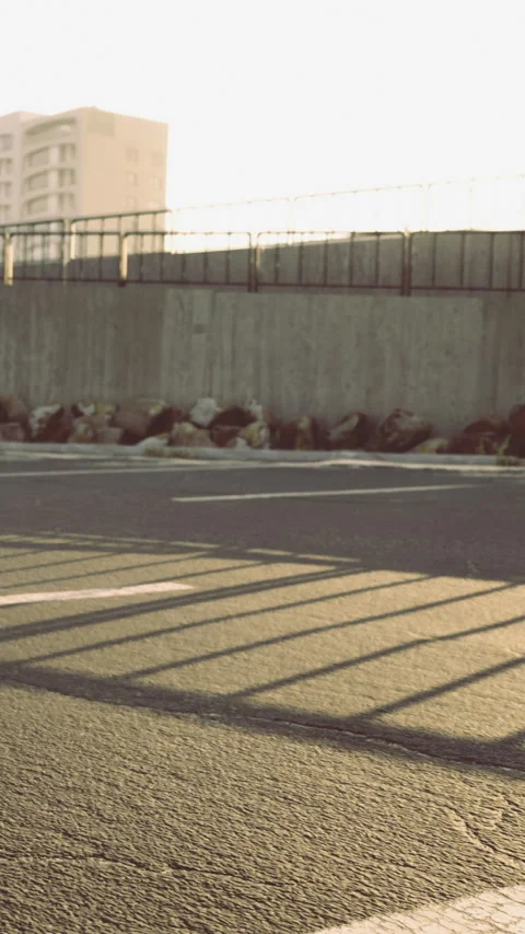 Sunset light cast shadows on the road near a concrete wall with rocks Stock Footage 334688455