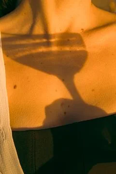 Sunset light casts a shadow of a glass on a person's skin during a summer gat Stock Photos