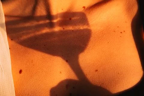 Sunset light casts a shadow of a glass on a person's skin during a summer gat Stock Photos