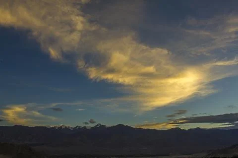 Sunset light in the clouds in the dark blue sky over the mountains with snowy Foto stock