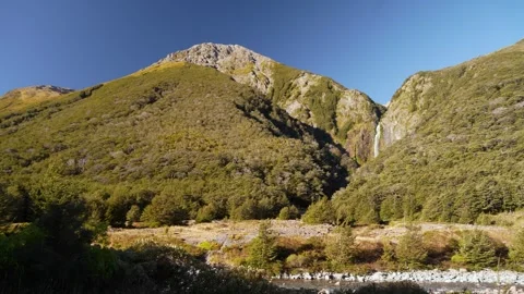 Sunset light hits Devils Punchbowl waterfall in lush forested New Zealand Stock Footage 310769162