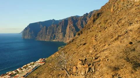 Sunset light illuminate steep Los Gigantes cliifs rocky barren volcanic Video stock 225901183