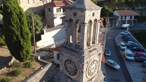 Sunset light illuminates bell tower with clock while cars exit parking Stock Footage 325221288