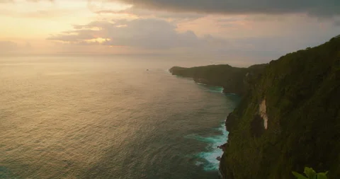 Sunset light illuminates the rugged cliffs and coastline of Nusa Penida Island Stock Footage 345687582