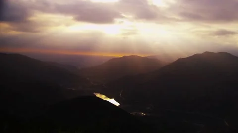 Sunset light illuminates valley through mountain peaks Stock Footage 329545621