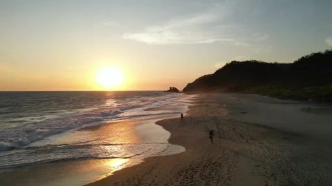 Sunset Light Illuminating Gentle Ocean Waves and people on Empty Sand Vídeos de archivo 321707619