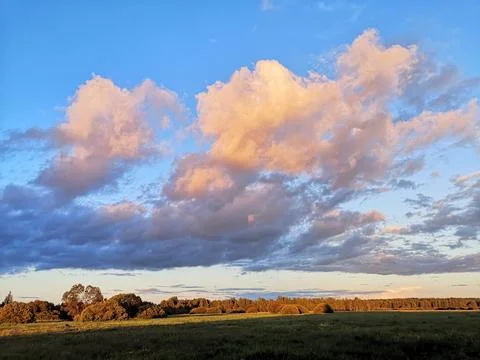 Sunset light painting clouds over rural field Stock Photos