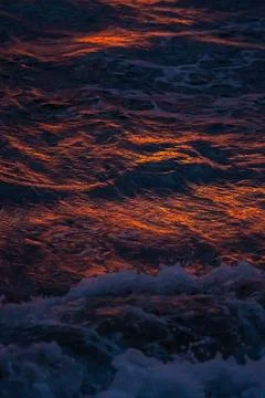 Sunset light reflections on ocean surface with vivid orange tones Stock Photos